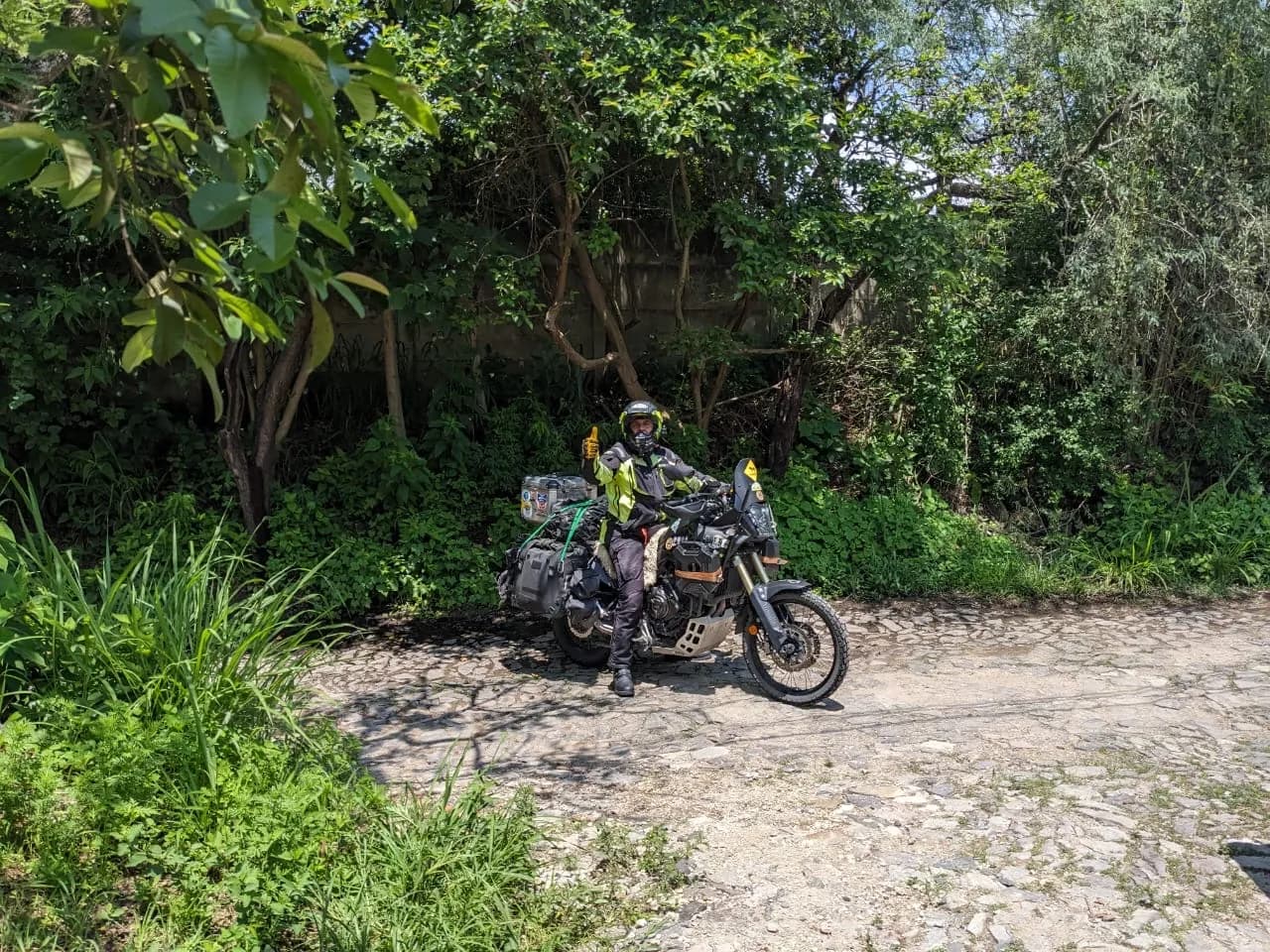 Motoviajero Gustavo Correa apoyado en su moto frente al cartel oficial de Alaska
