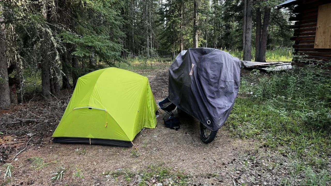 Motorcycle and tent camping in a wooded area of Alaska