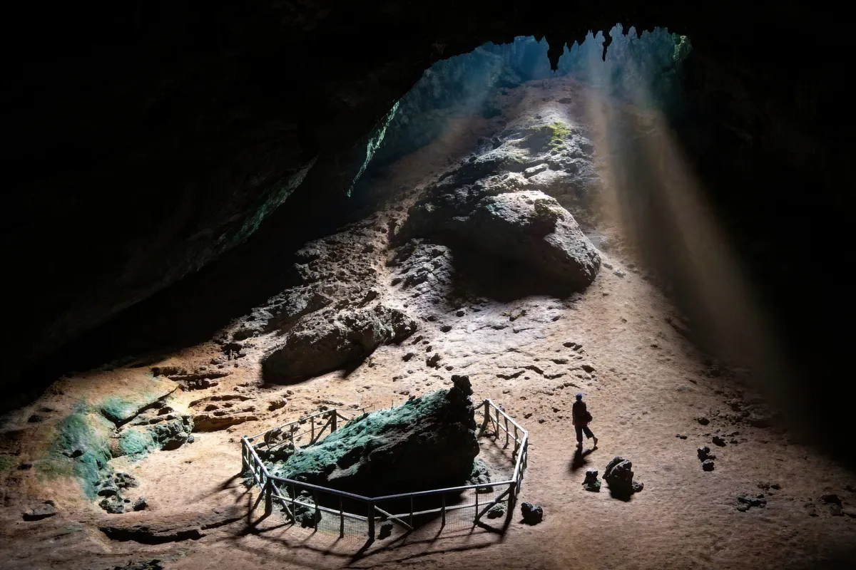 Interior de una gran cueva del sur de Tailandia con un haz de luz entrando por el techo