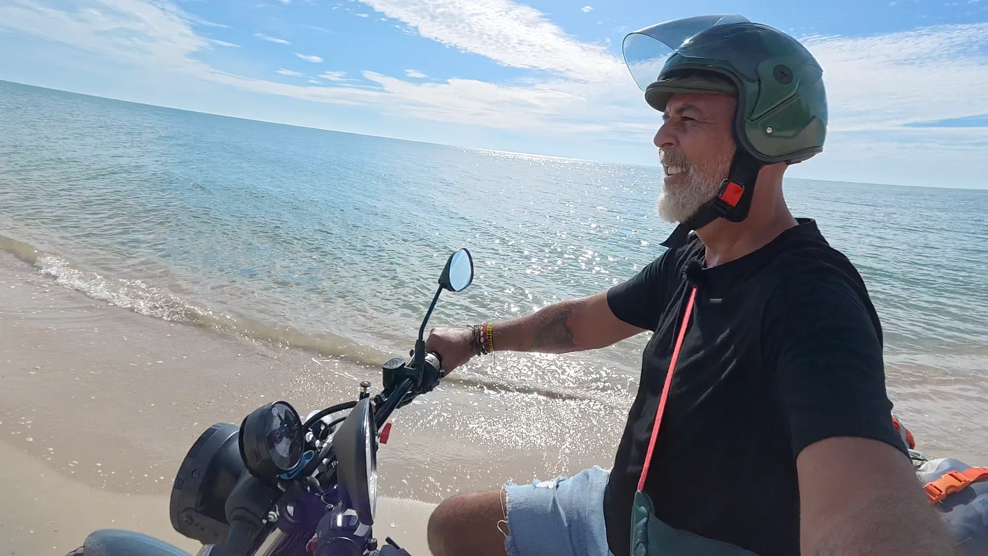 Gustavo Correa conduciendo una moto de baja cilindrada por la orilla de una playa vacía en el sur de Tailandia