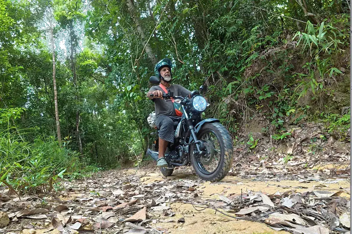 Gustavo Correa con su moto en un camino rural del sur de Tailandia