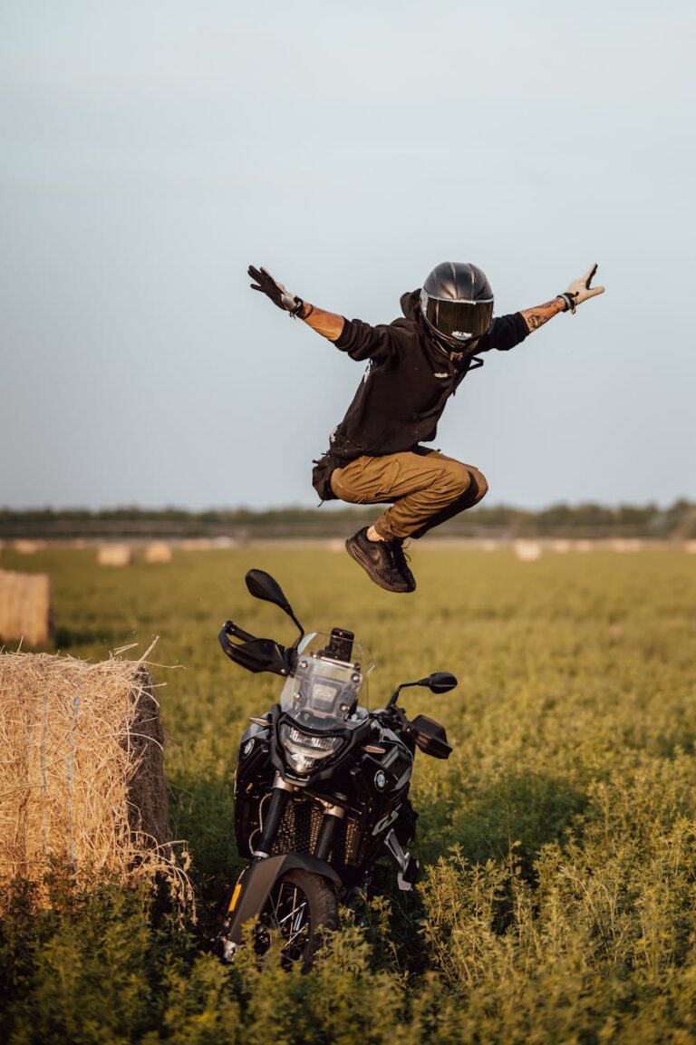 person jumping over motorcycle in field