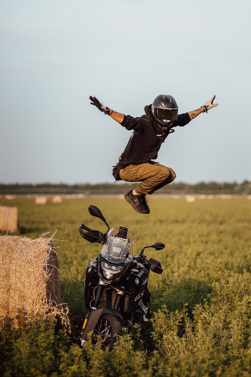 person jumping over motorcycle in field